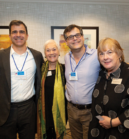 Two women and two men, smiling, with their arms around one another's backs